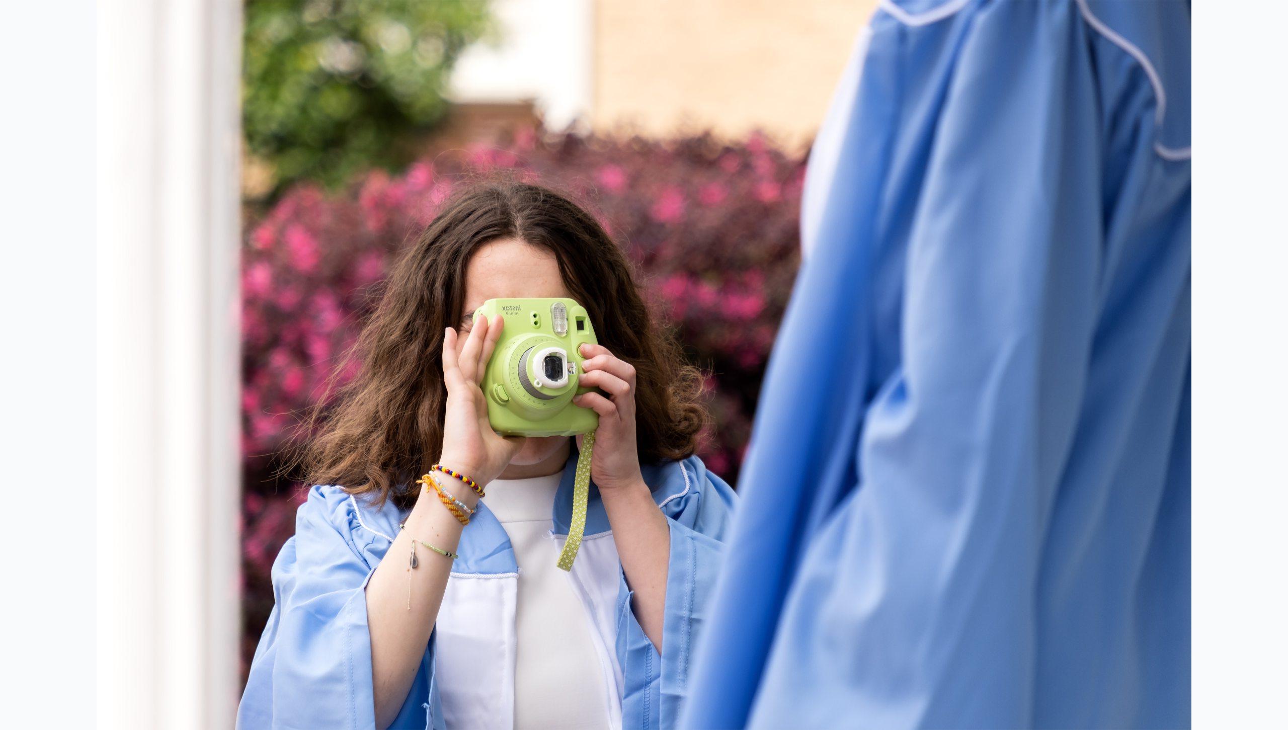 A student taking a picture with a film camera.